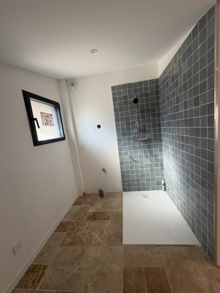 Salle d'eau rénovée avec douche à l'italienne et carrelage bleu